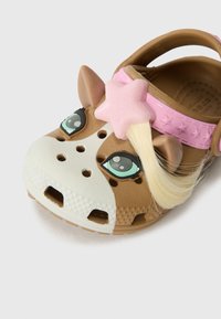 Brown and white clogs shaped like a horse's head, featuring large eyes, a pink star accent, and a blonde hair attachment.