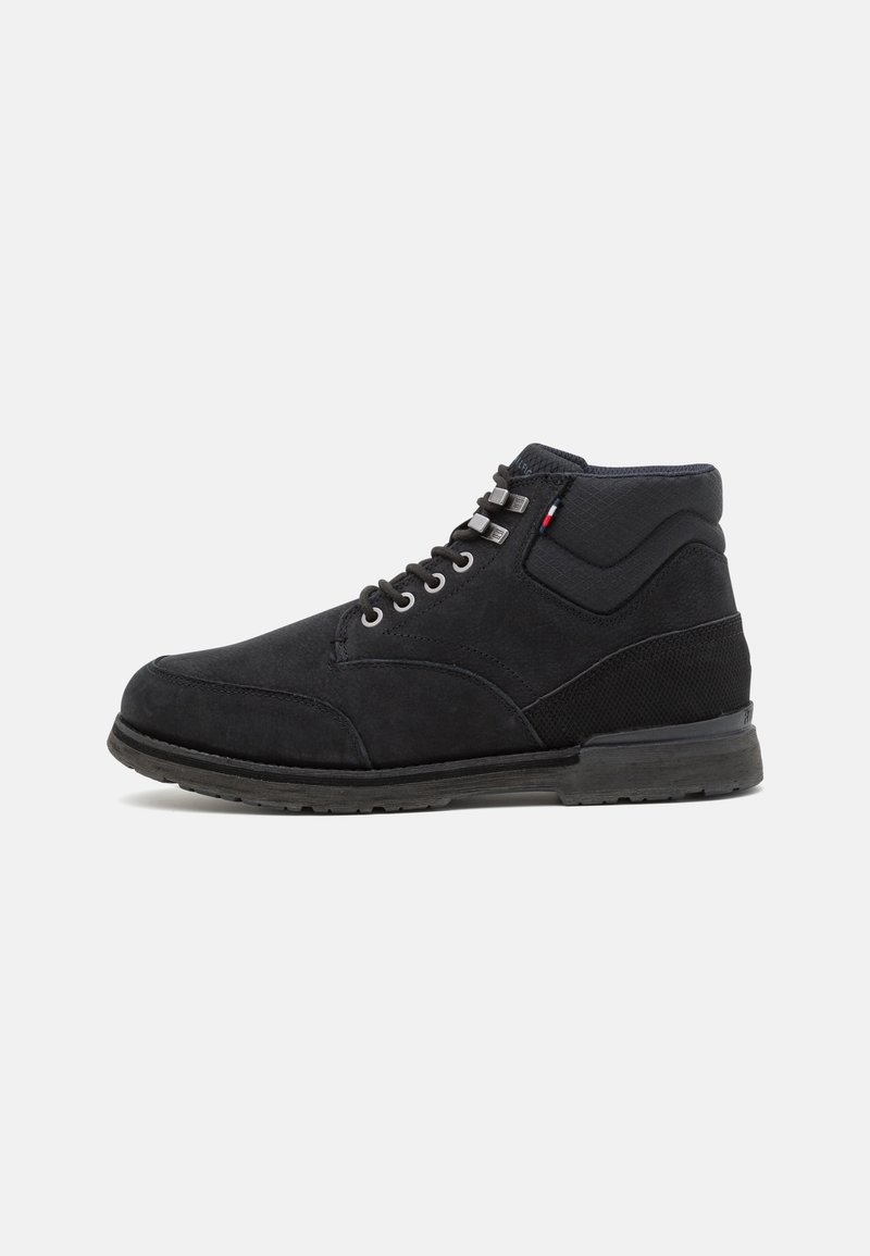 Bottes montantes noires en daim avec un panneau en maille texturée, un design à lacets, des œillets en métal et une semelle en caoutchouc robuste.