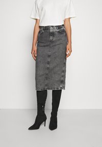 Harmaa farkku midi-hame suoran leikkauksen, etusauman ja haalistuneen pinnan kanssa. Yhdistetty polveen asti ulottuviin mustiin korkokenkiin.