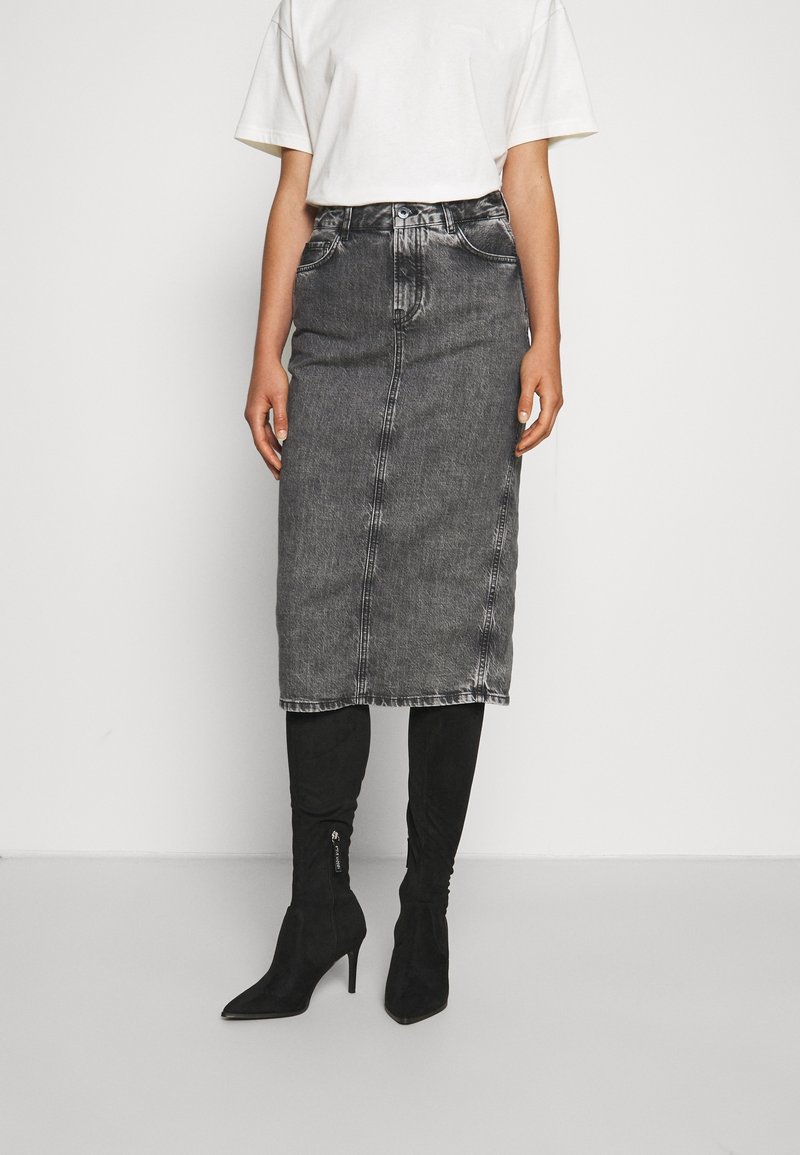 Harmaa farkku midi-hame suoran leikkauksen, etusauman ja haalistuneen pinnan kanssa. Yhdistetty polveen asti ulottuviin mustiin korkokenkiin.