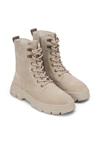 Bottes de cheville en suède beige avec une semelle robuste, un devant lacé et une fermeture éclair sur le côté. Quincaillerie en bronze et accent en boucle marron au talon.