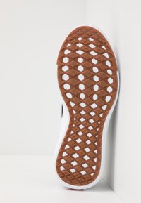 Suola della scarpa con un fondo in gomma texturizzata marrone con un motivo a diamante e bordo bianco. Superficie superiore liscia con un sottile contrasto di colore.
