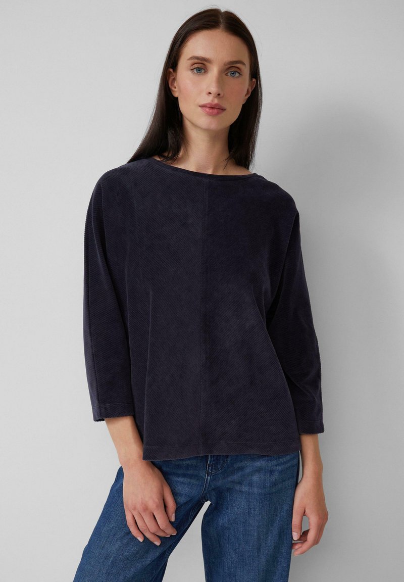 Navyblauwe corduroy top met een brede halslijn, driekwartmouwen en een ontspannen pasvorm. Gev textured oppervlakte met verticale ribbels.