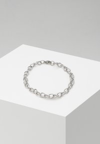 Bracciale in metallo argento con anelli sagomati interconnessi. Superficie liscia con finitura lucida. Design della chiusura sicura.