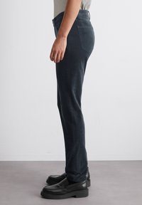 Donker denim broek met een slim fit, met een vijf-pocket ontwerp en een gladde textuur, gedragen met zwarte instapschoenen.