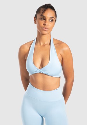 Sports bra azzurro chiaro con stile a halter e design frontale attorcigliato, realizzato in tessuto elasticizzato. Pantaloni a vita alta coordinati presentano una texture a coste.