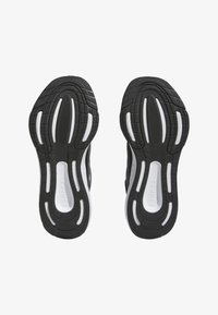 Scarpe da ginnastica nere con suole in gomma testurizzata e dettagli bianchi. Presentano un battistrada pattern per una maggiore aderenza e supporto.