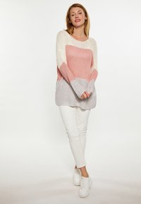 Pulover tricotat cu un design color-block în roz, crem și gri. Croi lejer, cu mâneci lungi și manșete ribbate, asociat cu pantaloni albi.