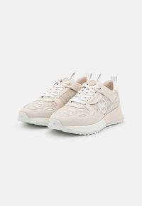 Beige lenkkarit, joissa on mokkanahka ja kuvioitu tekstiilipinta. Varustettu valkoisilla nauhoilla, logotiedoilla ja tekstuurilla varustettu pohja pidon parantamiseksi.