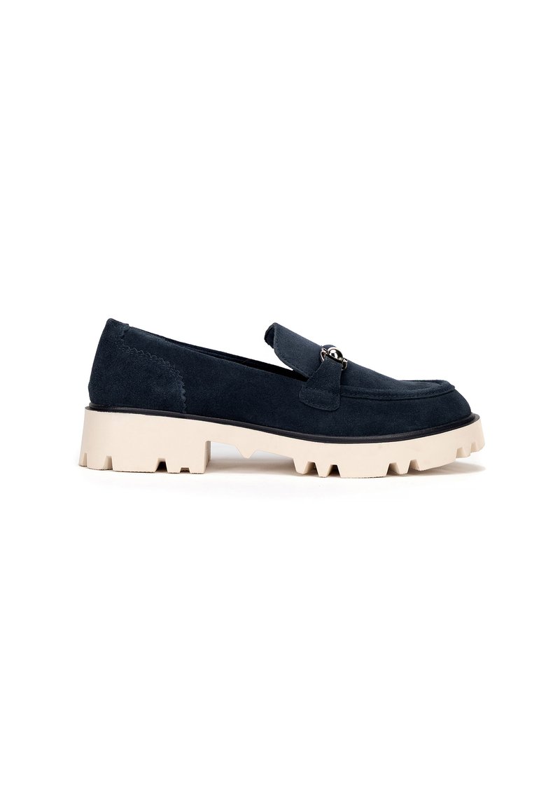 Mocasines de ante azul marino oscuro con suela beige gruesa, que cuentan con una tira frontal y acento de hardware metálico. Diseño simple y elegante con acabado texturizado.