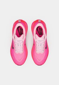 Ljusa rosa och röda Nike Vomero Plus löparskor sedd ovanifrån, med svart swoosh och texten "RUN" inuti sulorna.