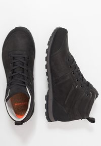 Schwarze Wanderschuhe aus synthetischem Material mit einer strukturierten Oberfläche, ausgestattet mit Schnürsenkeln, einer robusten Sohle und einem leicht erhöhten Knöchldesign.