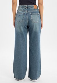 Jeansy dżinsowe w kolorze jasnoniebieskim o szerokich nogawkach, z wysokim stanem, tylnymi kieszeniami z haftem oraz skórzaną metką na tylnej części pasa.