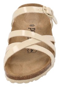 Infradito beige con cinturini sintetici lucidi in design incrociato. Include una fibbia e una soletta testurizzata di colore naturale.
