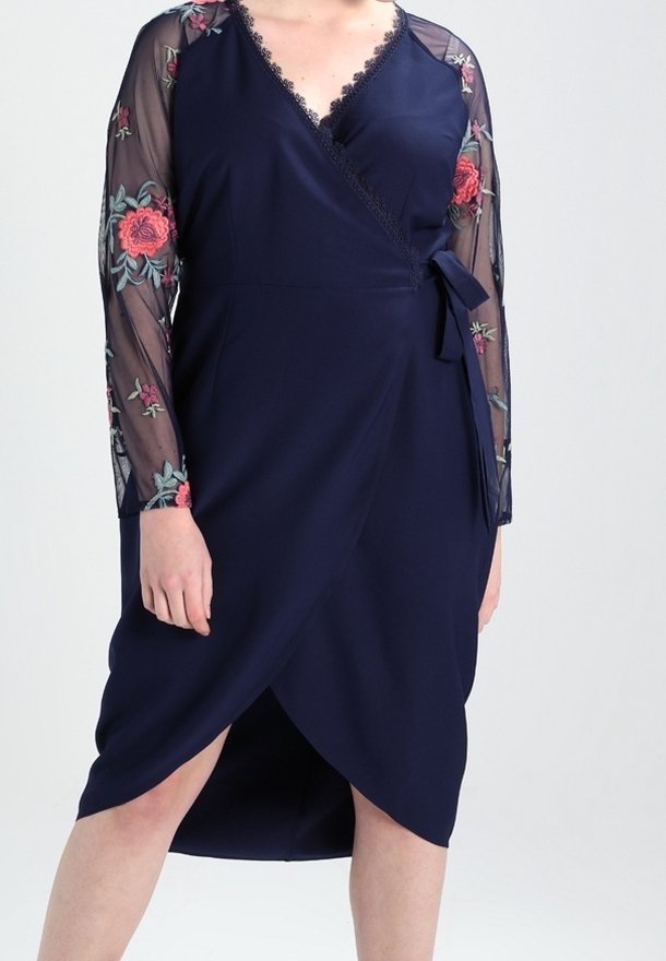 Robe portefeuille bleu marine avec manches en tulle brodées de fleurs, bordure en dentelle et ceinture à nouer. Dotée d'une jupe longueur genou avec un ourlet en biais.