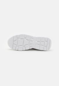 Sole of a sneaker featuring a thick, textured white rubber with a patterned tread for grip and traction. Flat, rounded toe design.