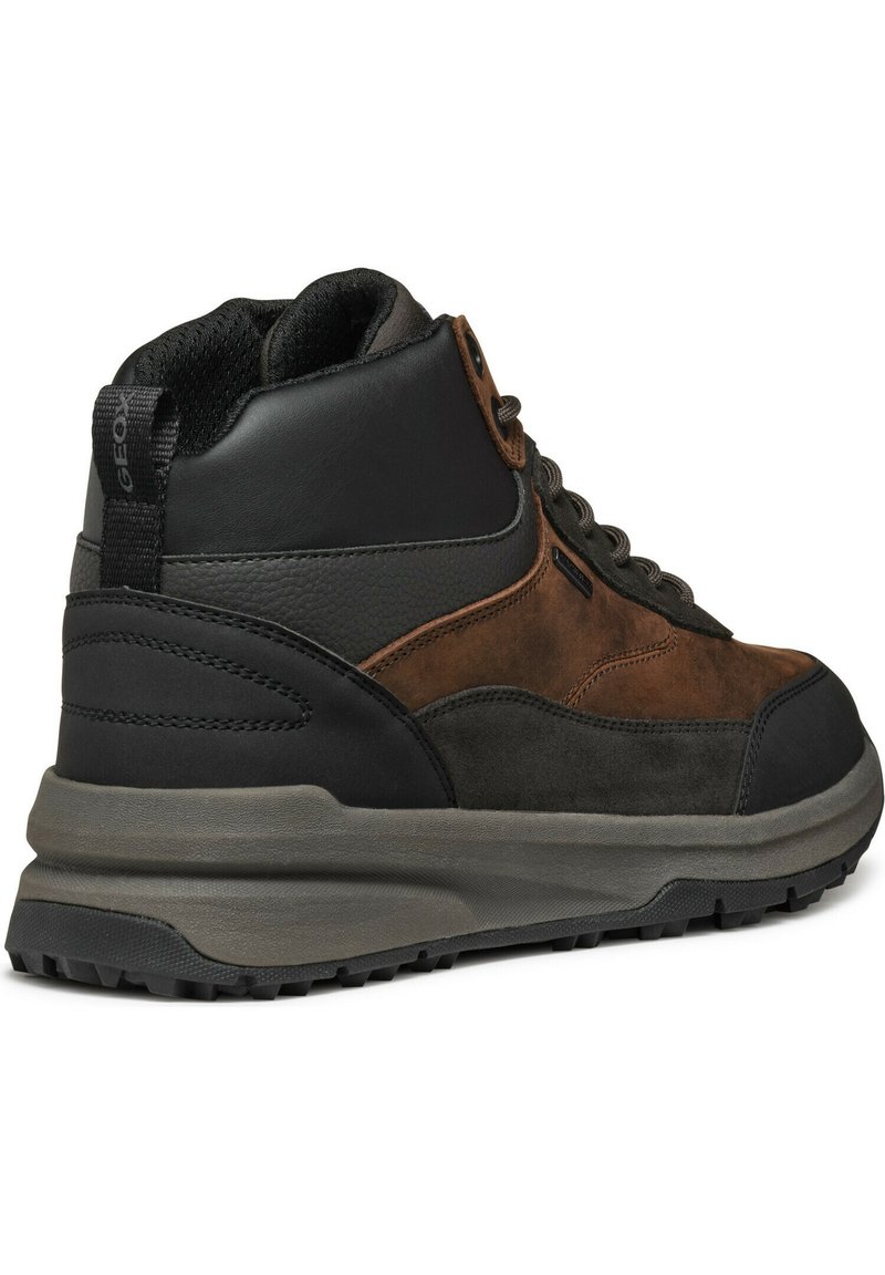 Stivale da trekking mid-top con una combinazione di suede marrone e pelle nera, pannelli testurizzati, dettagli marroni e una suola in gomma grigia spessa con trazione.