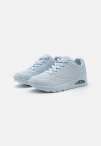 Light blue sneaker with a smooth synthetic upper, perforated accents, lace-up design, and visible air cushioning in the sole. Rounded toe.