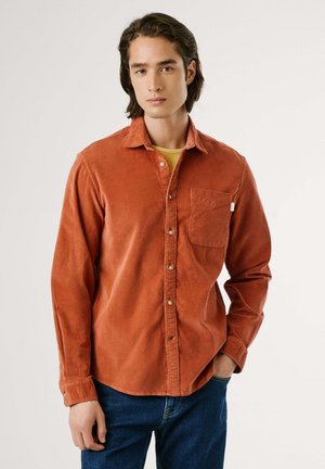 Roodbruine, knoopsluiting shirt gemaakt van zachte, gestructureerde stof, met een borstzak en een klassieke kraag. Gepaard met blauwe spijkerbroek.