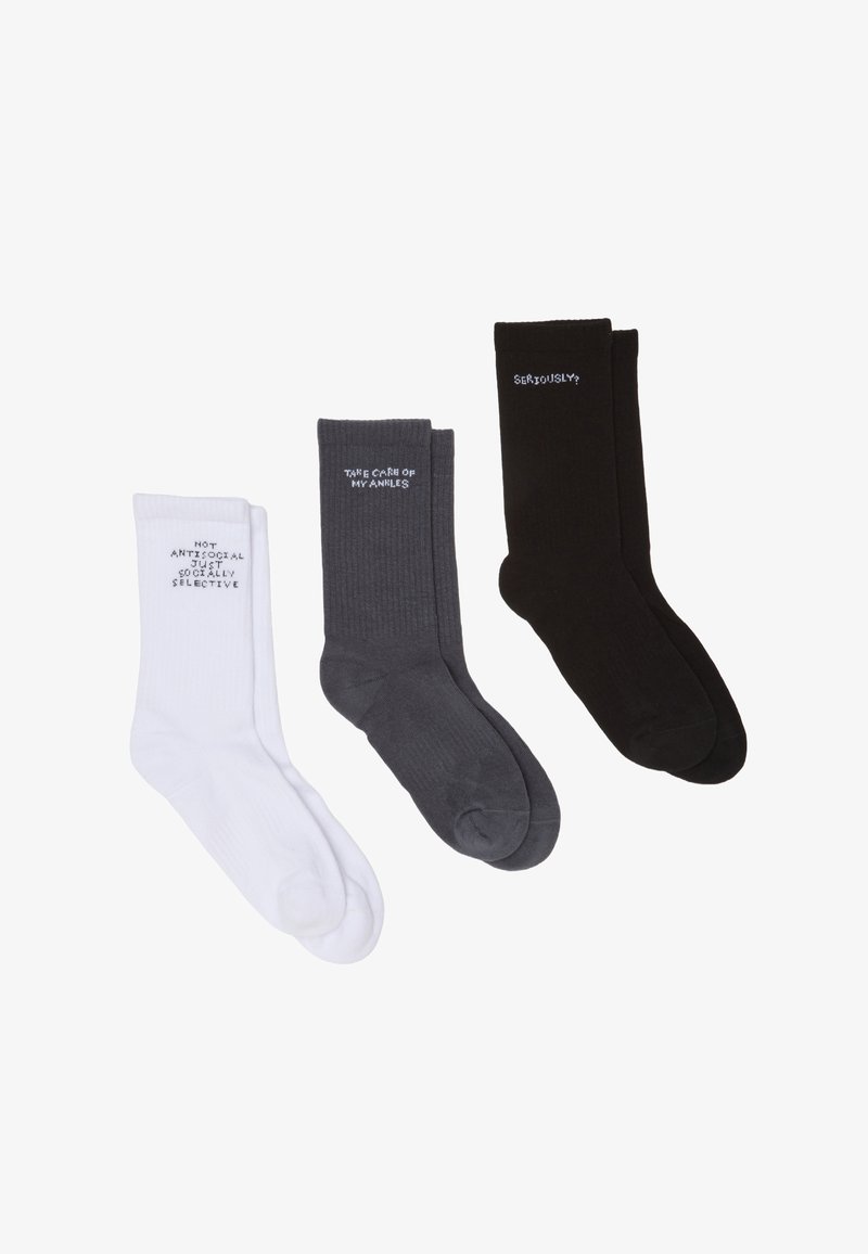Drei Paar Knöchelsocken: weiß, grau und schwarz, mit kontrastierenden Textdrucken. Der Stoff wirkt weich und hat eine gerippte Textur.