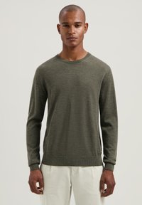 Olijfgroene wollen trui met ronde hals, lange mouwen en knooploze boorden. Heeft een gladde textuur met een subtiel breipatroon.