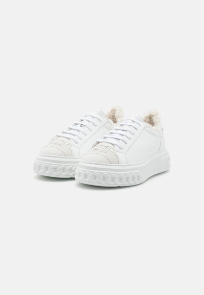 Baskets blanches en cuir lisse avec un bout texturé, dotées d'un col duveteux, de lacets blancs et d'une semelle épaisse tressée.