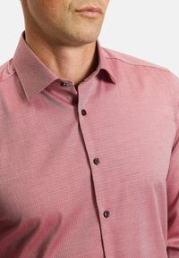Red patterned dress shirt with a standard collar, featuring purple buttons and a textured fabric with a geometric design.