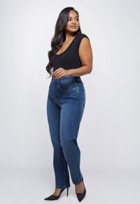 Hoge taille blauwe denim jeans met een slim fit, voorzien van voorzakken, een knoopsluiting en een soepele textuur, gecombineerd met een zwarte ribgebreide bodysuit.