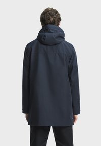 Marinblå vattentät jacka med huva, med rak skärning, långa ärmar och slät yta. Inga synliga mönster eller detaljer.