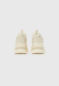 Pair of beige chunky sneakers shown from the back on a plain white background.
