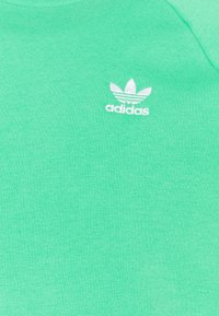 Felpa di cotone verde con logo Adidas trefoil bianco sul petto a sinistra. Tessuto morbido con design classico a girocollo.