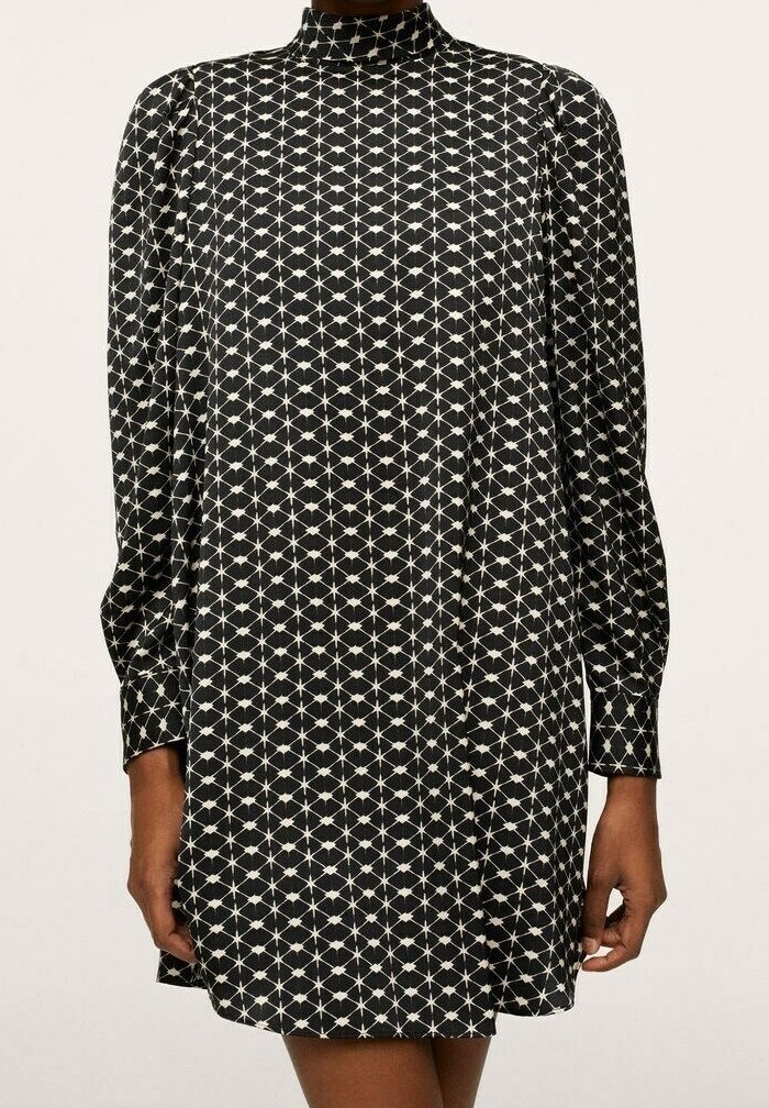 Robe noire à manches longues avec un col haut comportant un motif géométrique blanc en losange et points, portée par une personne les bras relâchés le long du corps.