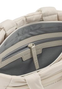 Sisustuksessa on vaaleancremivärinen kangaslaukkua, jossa on harmaa vuori. Varustettuna vetoketjullisella taskulla, jossa on "KAPTEN & SON" -tunnus. Pehmeä ja sileä pinta.