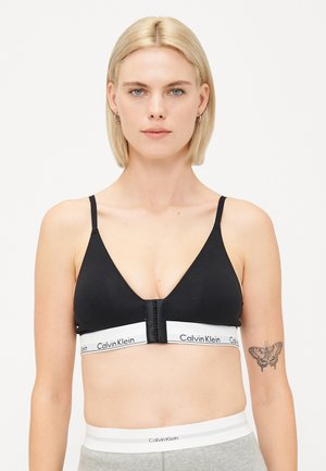 Reggiseno wireless nero con design a V, spalline regolabili e un elastico bianco con marchio caratterizzato da più ganci.