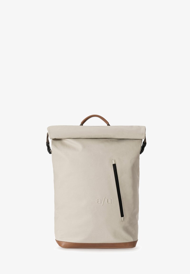 Roll-top backpack in light beige material with a brown leather base, featuring a side zipper pocket and a top leather handle.