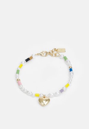 Helmipantti, jossa on kultainen sydänkoru, valkoisia helmiä ja värikkäitä sylinterimäisiä aktsentteja vaaleanpunaisena, keltaisena, vihreänä, sinisenä ja mustana.