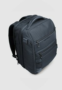 Mochila negra con textura de patrón de diamante, múltiples compartimentos con cremallera, respaldo acolchado y correas ajustables para mayor comodidad.