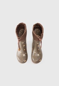 Botas de goma marrones con un interior texturizado y un cordón en la parte superior. Decoradas con patrones de planetas y estrellas en la superficie exterior.