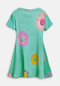 Grön bomullsklänning med korta ärmar, med broderade blommor i rosa, gult och blått på en ribbad textur. Utställd kjoldesign.