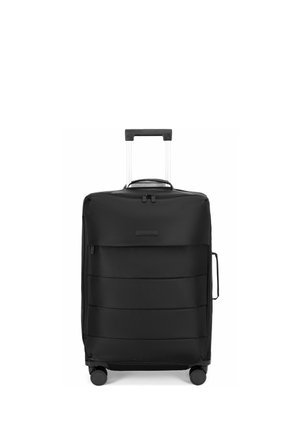Valise souple noire verticale avec poignée télescopique, poignée latérale, quatre roues et poche zippée à l'avant sur fond blanc.