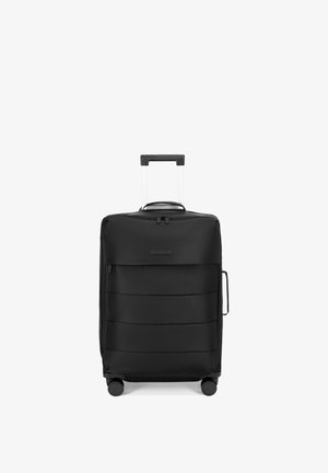 Valise souple noire verticale avec poignée télescopique, poignée latérale, quatre roues et poche zippée à l'avant sur fond blanc.