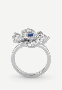 Srebrny pierścionek w kształcie kwiatu z centralnym niebieskim kamieniem szlachetnym, otoczonym mniejszymi przezroczystymi kamieniami, z polerowaną obrączką.
