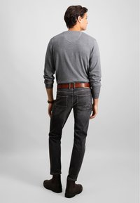 Grå langermet genser med raglanermer, kombinert med mørke jeans og brunt lærbelte. Sorte ankelstøvler fullfører antrekket.