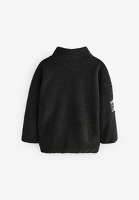 Pull en polaire noir avec un col montant, coupe décontractée et manches larges. Présente une étiquette sur la manche gauche. Matériau doux et texturé.