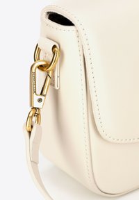 Sac à main en cuir crème de forme rectangulaire, avec un fermoir en métal doré et une texture lisse. Détails de couture le long des bords.