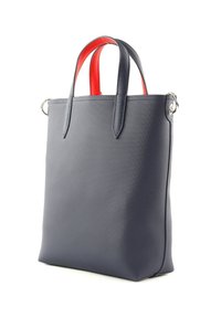 Sac fourre-tout bleu marine en matériau texturé, avec des poignées rouges et des accents en métal argenté. Forme rectangulaire avec un design robuste.