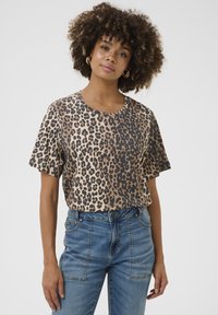 Leopard print short-sleeve t-shirt in beige and brown, featuring a round neckline and loose fit, paired with light blue jeans.