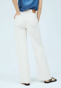 Kerman levele hitam yang terbuat dari denim. Dilengkapi dengan lima saku, pinggang tinggi, dan label merah "Pepe Jeans" yang terlihat di pinggang belakang.