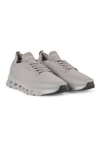 Scarpe sportive grigie con tomaia in maglia testurizzata, linguetta imbottita e suola in gomma flessibile dotata di cuscinetti d'aria allungati per il supporto.