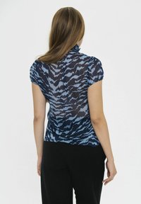 Zila rakstota blūze ar īsām uzpūstām piedurknēm un krokotu apkakli. Caurskatāms audums ar viļņotu abstraktu rakstu tumšāk zilās krāsās.